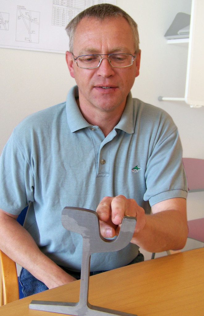 Jörgen Höjer med en tvärsektion av en kurvskena. I fördjupningen, där han håller fingrarna, läggs smörjfettet.